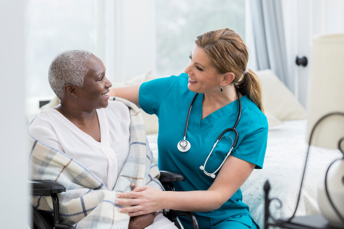 Caring nurse talks with senior female patient